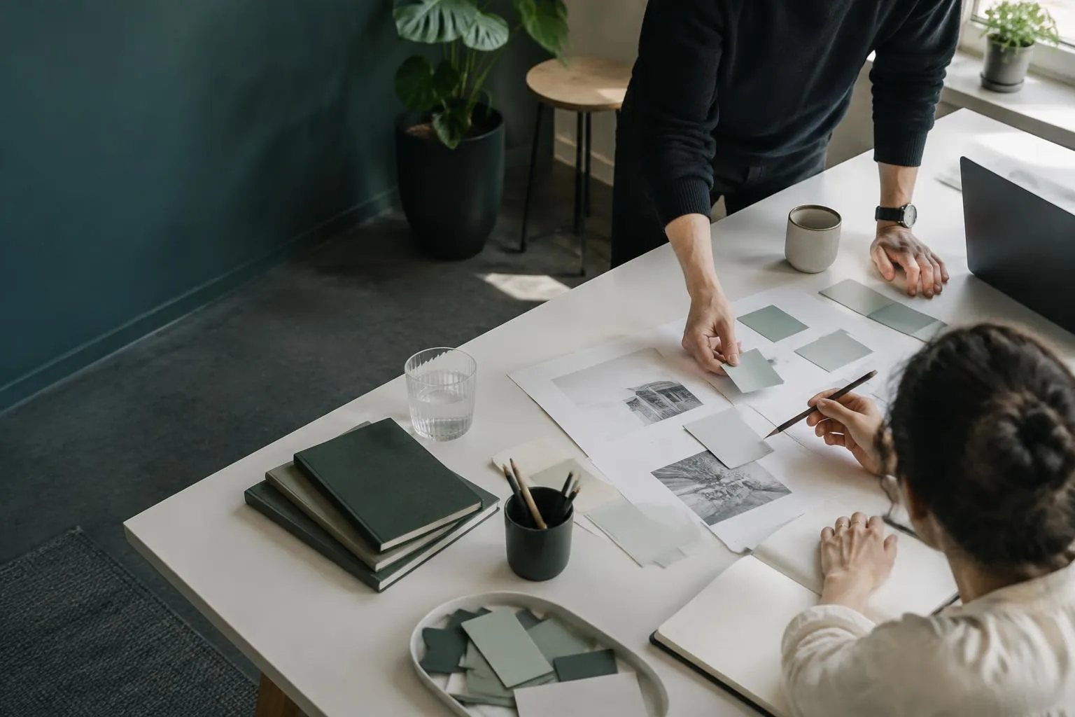 Dos personas revisando materiales de planificación sobre una mesa de trabajo; imagen generada.
